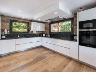Experience modern luxury in this stunning kitchen, featuring sleek white cabinetry and a rustic wood-paneled backsplash.