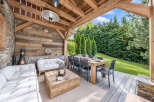 Experience outdoor living at its finest in this covered patio space, featuring a cozy seating area with a fireplace and a spacious dining table perfect for entertaining.