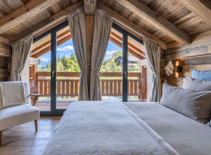 Experience rustic luxury in this charming chalet bedroom, featuring a cozy bed and a comfortable armchair.