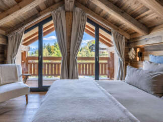 Experience rustic luxury in this charming chalet bedroom, featuring a cozy bed and a comfortable armchair.