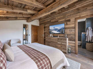 Experience rustic luxury in this charming bedroom, featuring a cozy bed with plaid accents and a plush throw.