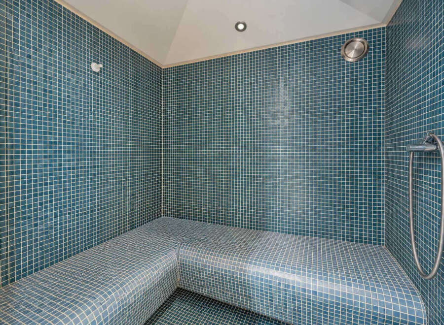 Experience ultimate relaxation in this beautifully tiled steam room, featuring comfortable, built-in seating perfect for unwinding.
