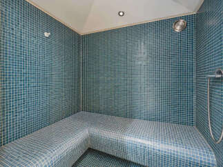 Experience ultimate relaxation in this beautifully tiled steam room, featuring comfortable, built-in seating perfect for unwinding.
