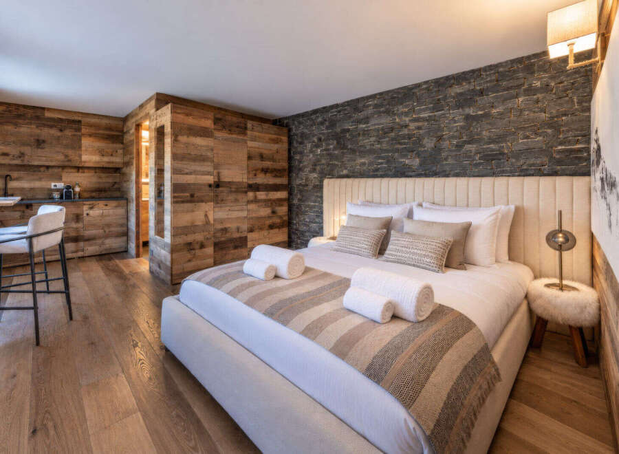 Experience rustic luxury in this beautifully appointed bedroom, featuring a cozy king-size bed with plush linens and decorative pillows.