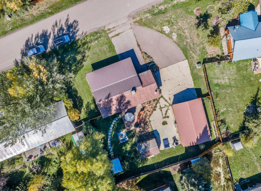 Discover this charming property featuring multiple buildings with distinct roofing, including a prominent blue metal roof and several brown metal roofs.