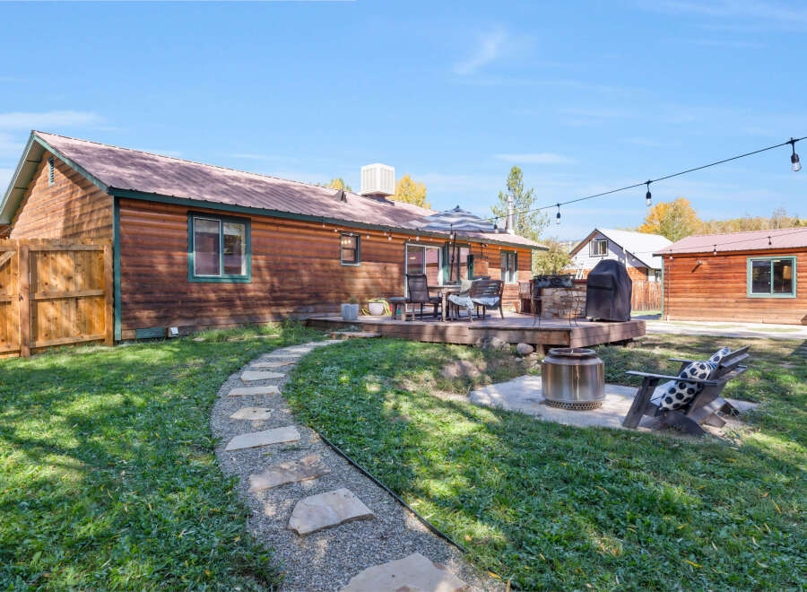 Enjoy outdoor living with this charming backyard featuring a spacious wooden deck, perfect for entertaining.