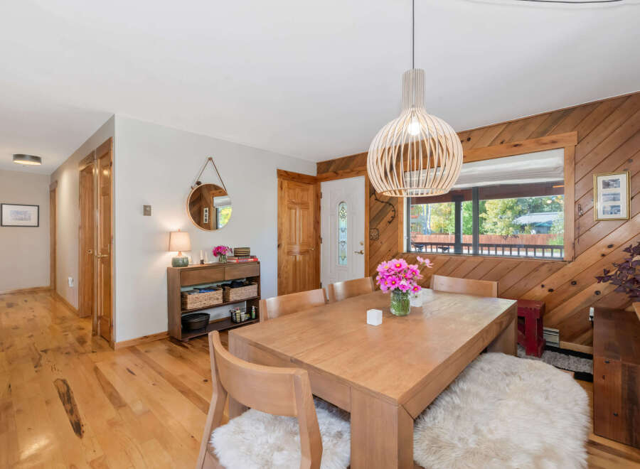 Experience cozy dining in this charming space, featuring a warm wooden dining table set against a backdrop of rustic wood-paneled walls.