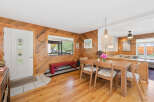 Step into a warm and inviting living space featuring a charming dining area with a light wood table and chairs adorned with cozy sheepskin cushions.