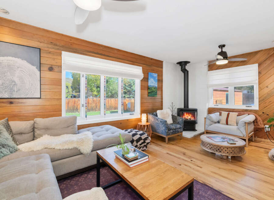 Experience cozy living in this inviting living room, featuring warm wood-paneled walls and a charming fireplace.