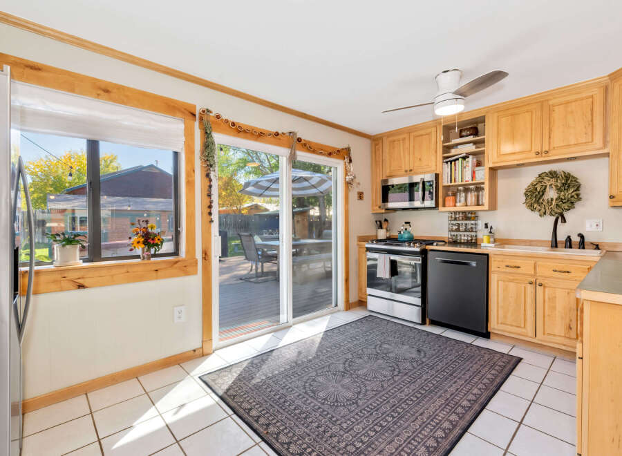 This charming kitchen features light wood cabinetry, a stainless steel gas range, and a black dishwasher.
