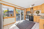 This charming kitchen features light wood cabinetry, a stainless steel gas range, and a black dishwasher.