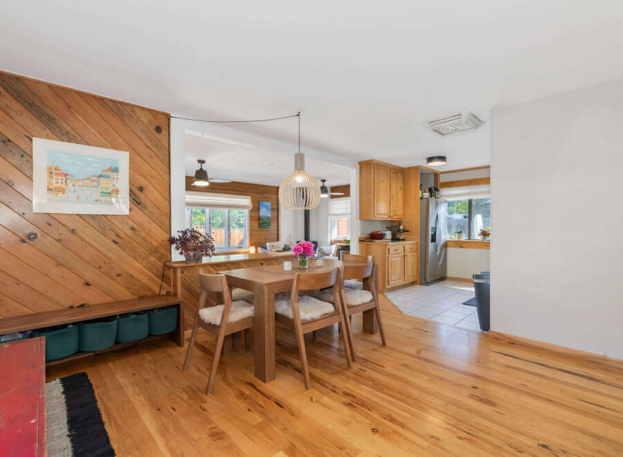 This charming dining area and kitchen features warm wooden accents, including a slatted pendant light and a diagonal wood-paneled wall.
