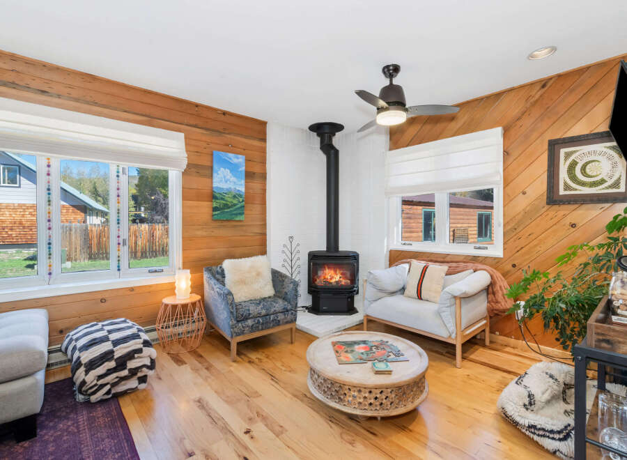 Cozy living room featuring a modern wood-burning stove as the focal point, complemented by comfortable seating and warm wood paneling.