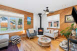 Cozy living room featuring a modern wood-burning stove as the focal point, complemented by comfortable seating and warm wood paneling.