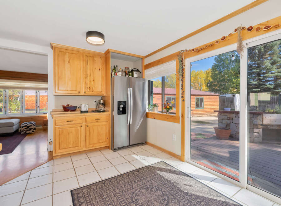 This charming kitchen features light wood cabinetry, a stainless steel refrigerator, and a tiled floor.