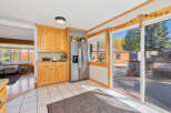 This charming kitchen features light wood cabinetry, a stainless steel refrigerator, and a tiled floor.