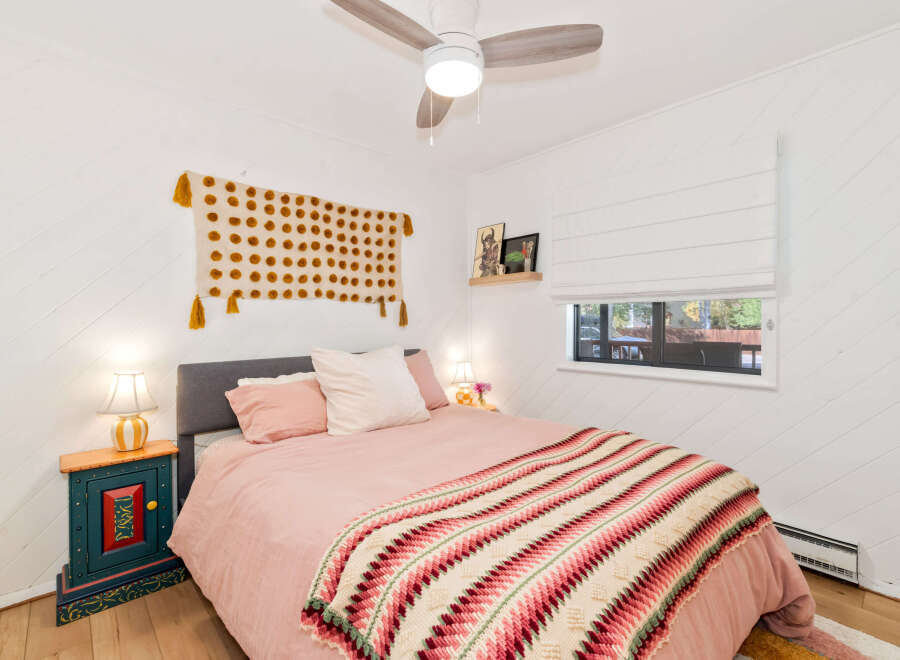 This charming bedroom features a cozy pink bed adorned with a colorful, textured throw blanket.