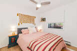 This charming bedroom features a cozy pink bed adorned with a colorful, textured throw blanket.