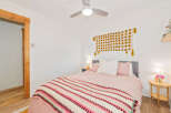 This charming bedroom features a cozy queen-size bed adorned with soft pink linens and a vibrant, patterned throw blanket.