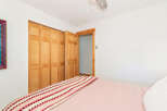 This bedroom features a large bed with a pink comforter and a colorful striped throw blanket.