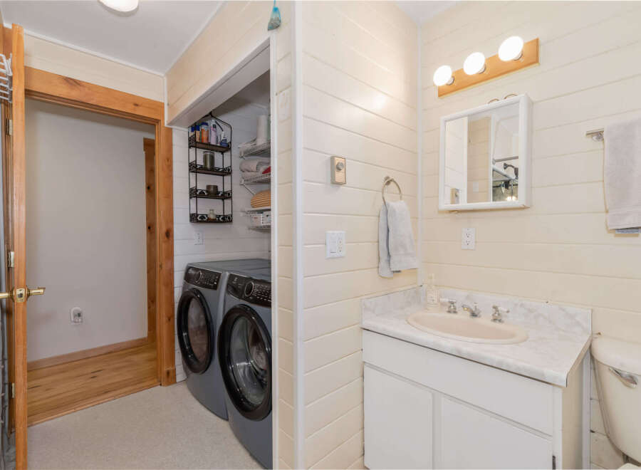 This charming bathroom features a convenient in-unit laundry area with a washer and dryer, perfect for modern living.
