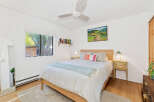 This charming bedroom features a comfortable queen-size bed with crisp white linens and a light blue throw blanket.