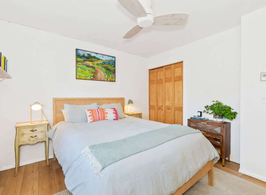 Discover this charming bedroom featuring a comfortable bed adorned with decorative pillows and a light blue throw.