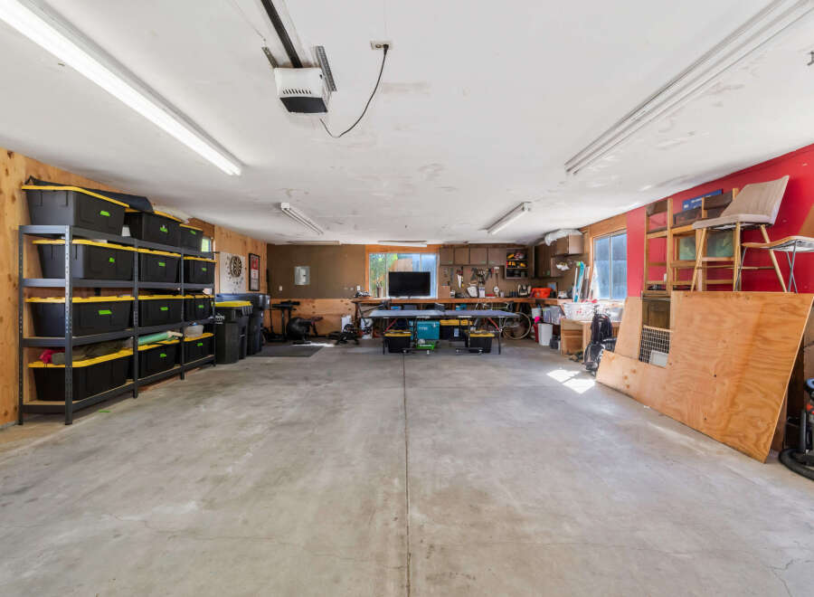 This spacious garage offers ample storage solutions with multiple shelves filled with black and yellow bins, perfect for organizing your belongings.