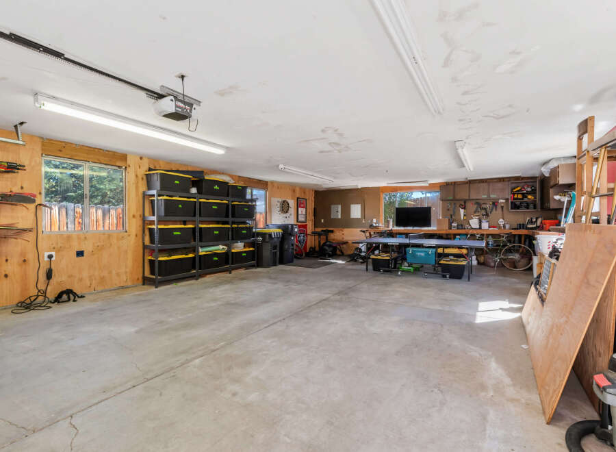 This spacious garage offers ample storage solutions with multiple shelves filled with black and yellow bins, perfect for organizing your belongings.