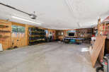 This spacious garage offers ample storage solutions with multiple shelves filled with black and yellow bins, perfect for organizing your belongings.