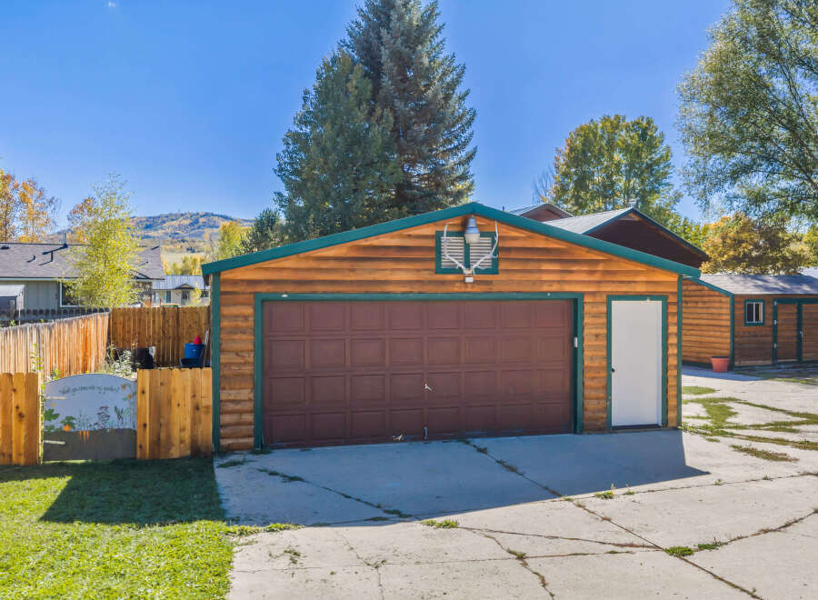 Discover this charming property featuring a spacious wooden garage with a rich brown door, complemented by a bright white side door.