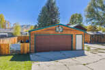 Discover this charming property featuring a spacious wooden garage with a rich brown door, complemented by a bright white side door.