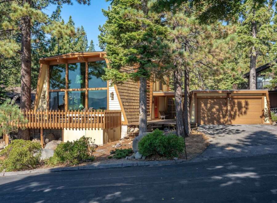 Nestled among tall pine trees, this unique A-frame home offers stunning natural light through its expansive floor-to-ceiling windows.