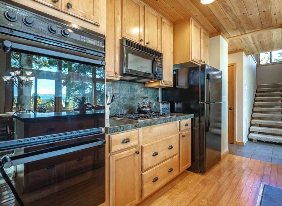 This spacious kitchen features a built-in oven and microwave, complemented by a gas stovetop and a black refrigerator.
