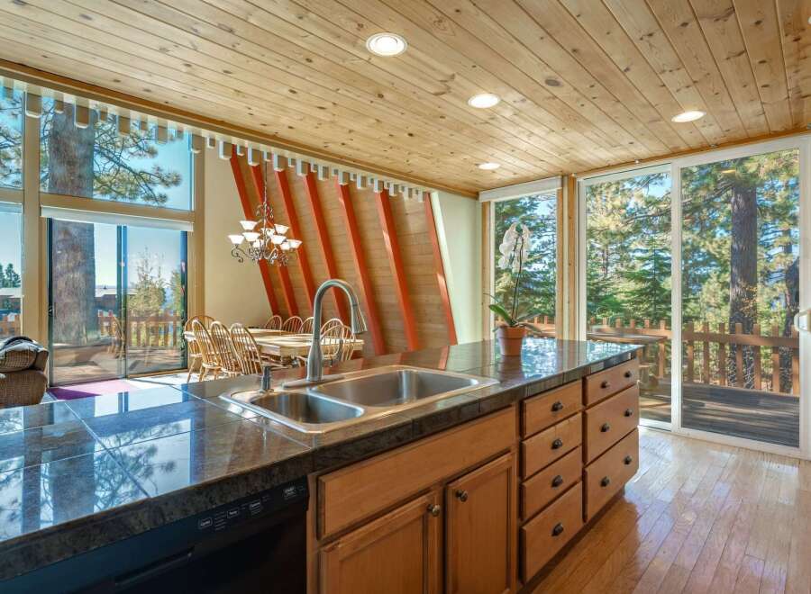 Experience breathtaking mountain views from this stunning kitchen and dining area, featuring a large island with a double sink and ample cabinet space.