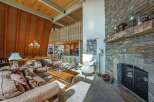 Experience rustic charm in this spacious living area, featuring a soaring wood-paneled vaulted ceiling with exposed beams and striking orange accents.
