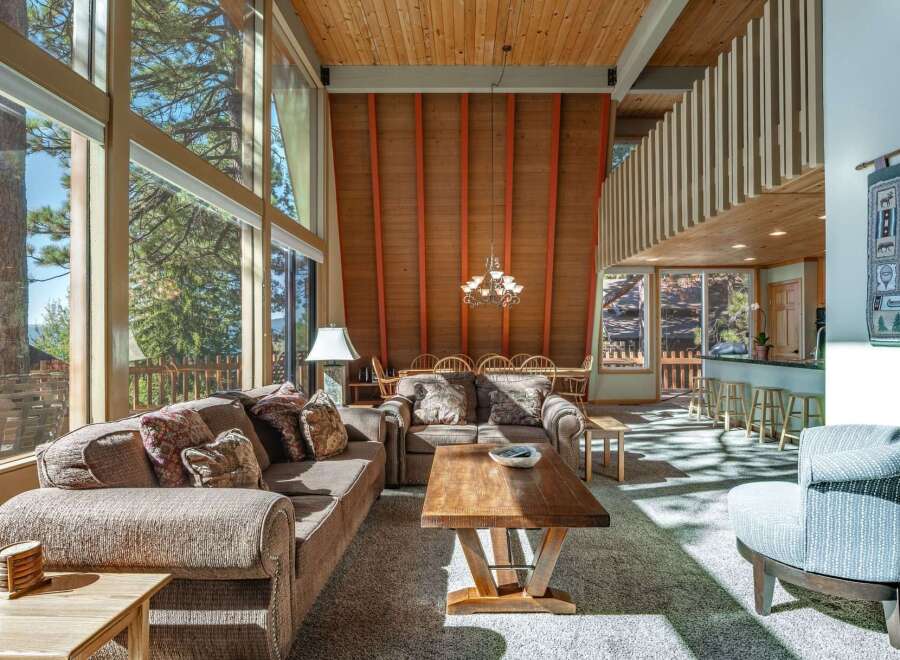Experience breathtaking mountain views from this stunning living room, featuring a soaring A-frame ceiling and expansive floor-to-ceiling windows.