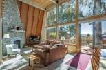 Experience breathtaking mountain views from this stunning living room, featuring a grand stone fireplace and expansive floor-to-ceiling windows.