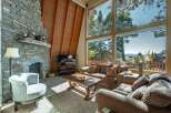 Experience breathtaking mountain views from this stunning living room, featuring a grand stone fireplace and soaring A-frame ceilings.