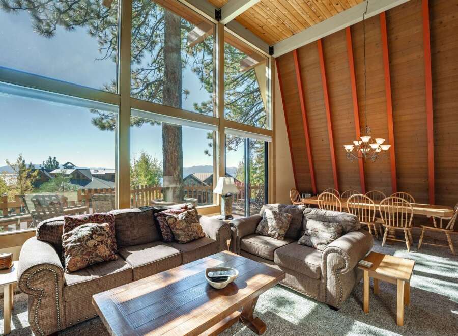 Experience breathtaking lake and mountain views from this stunning living room, featuring a wall of windows that floods the space with natural light.