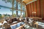 Experience breathtaking lake and mountain views from this stunning living room, featuring a wall of windows that floods the space with natural light.