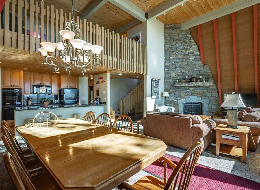 This spacious open-concept living area features a large wooden dining table perfect for family gatherings, adjacent to a modern kitchen with ample cabinet space and stainless steel appliances.