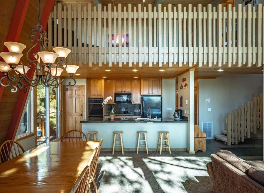 This spacious open-concept living area features a large wooden dining table perfect for family gatherings, adjacent to a well-equipped kitchen with ample cabinet space and a breakfast bar.