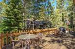 Enjoy outdoor living on this spacious wooden deck, perfect for entertaining or relaxing amidst the tall pine trees.