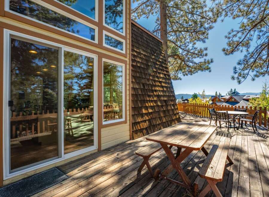 Enjoy the outdoors on this spacious wooden deck, featuring a picnic table and a separate dining set perfect for al fresco meals.