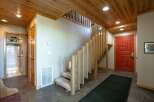 Step into a warm and inviting entryway featuring a striking red front door and a beautiful wooden staircase with a unique slatted railing.