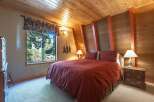 Experience cozy cabin living in this charming bedroom, featuring a rustic wood-paneled ceiling and walls that exude warmth.