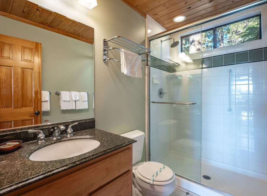 This bathroom features a spacious walk-in shower with a glass door and a rainfall showerhead, perfect for a relaxing experience.
