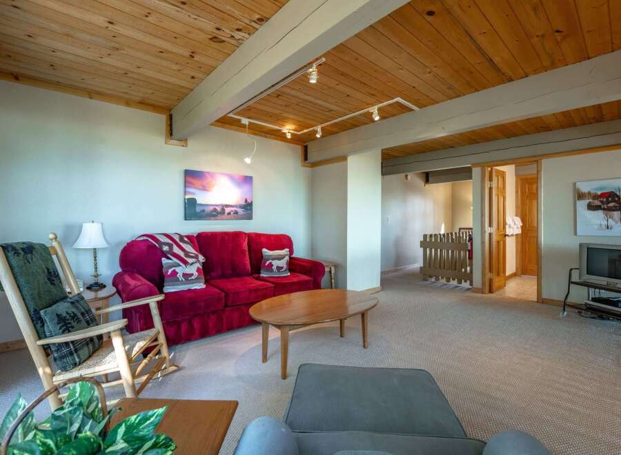 Step into this cozy living room featuring a plush red sofa adorned with decorative pillows and a rustic throw blanket.