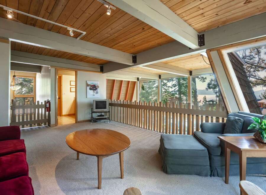 Experience breathtaking lake and mountain views from this stunning living area, featuring a vaulted wood-beamed ceiling and expansive windows.
